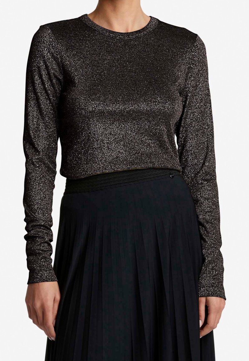 Svart långärmad topp med en metallisk, glittrig textur; rund hals; figurnära design som matchas med en plisserad svart kjol.