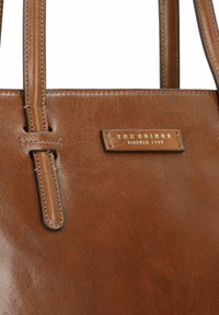 Borsa tote in pelle marrone con doppie maniglie, caratterizzata da una superficie testurizzata e una placca metallica con logo. Design semplice con dettagli hardware minimi.