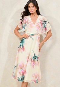 Vestido envolvente floral en tejido ligero, con patrones de flores en tonos rosa y verde azulado, mangas cortas con vuelo, escote en V y una silueta A-line fluida.