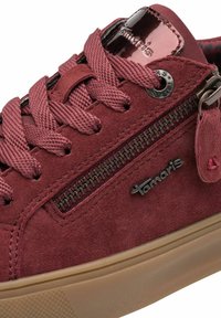 Sneaker in suede color bordeaux con lacci intrecciati, zip laterale, suola in gomma e dettagli lucidi. Presenta un logo e un motivo testurizzato sulla suola.