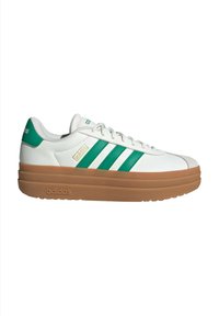 Vit lädersneaker med grön tre-stripes-design, gummibezig plattformssula och subtil märkning på sidan och hälen.