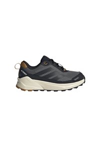 Chaussure d'extérieur noire et grise avec une tige texturée, trois bandes noires, une semelle intermédiaire gris clair et une semelle extérieure en caoutchouc robuste.