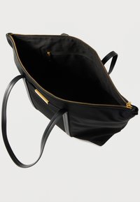 Μαύρη τσάντα ώμου από νάιλον με ομαλή υφή, χρυστό φερμουάρ και δύο ανθεκτικές μαύρες υφασμάτινες λαβές. Το εσωτερικό διαθέτει τσέπη με φερμουάρ για οργάνωση.