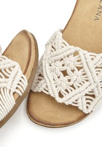 Sandali beige con un design in macramé sulla parte superiore, dotati di una morbida soletta simile alla pelle scamosciata e una suola in gomma resistente.