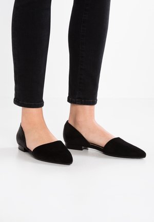 Schwarze flache Schuhe mit spitzem Zeh, vorne aus glattem Wildleder und hinten aus strukturiertem Mesh, auf einem flachen Absatz, kombiniert mit dunklen Jeans.