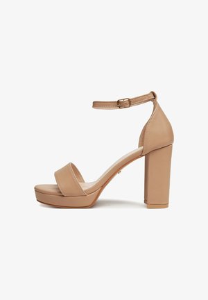 Sandalias nude de plataforma con tacón alto y ancho, una amplia tira frontal y una correa ajustable en el tobillo con una hebilla dorada. Textura de cuero suave.