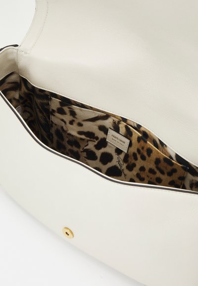 White leather handbag with a brown and black leopard print interior. Features a gold snap closure and a label inside. Rounded shape, smooth texture.