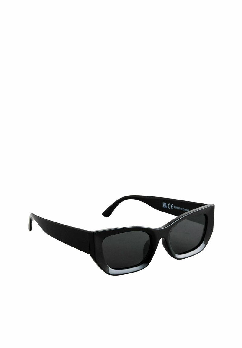 Lunettes de soleil noires avec une monture carrée épaisse ; verres teintés sombres avec un dégradé subtil ; texture lisse avec une marque visible sur la branche.