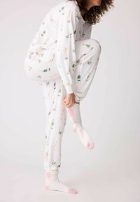 Vitt pyjamaset med champagneflaska och blommönster. Har lång ärm och elastiska manschetter. Mjuka, fluffiga vita strumpor med rosa detaljer.