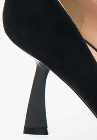 Czarne zamszowe szpilki z wysmukłą obcasem. Buty mają gładką teksturę i zaokrąglony nos. Wewnętrzna podszewka jest beżowa.