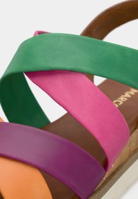 Värvikas sandaal, millel on ristised straps rohelisest, roosast, lilast ja oranžist. Valmistatud siledast nahast pruunist tallast ja heledast põhjast.
