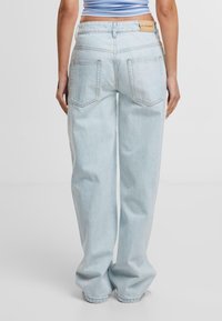 Lichtblauwe denim wijde jeans met een vervaagde textuur, met twee achterzakken en een merkenlabel op de tailleband.