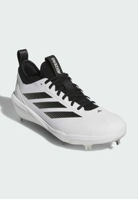 Baskets blanches avec accents noirs, présentant un dessus synthétique lisse, un motif perforé et un design bas. Clous en métal sur la semelle.