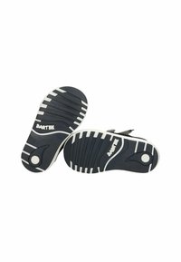 Due suole di scarpe in gomma nera con dettagli bianchi, caratterizzate da una texture rigata e un motivo di aderenza circolare. Logo "BARTEK" su una delle suole.
