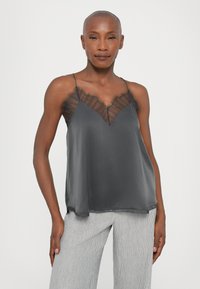 Satin gray camisole with a V-neck and sheer striped lace accents at the neckline. Thin straps and loose fit, paired with striped pants.