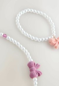 Två elastiska armband gjorda av vita pärlor, det ena med en rosa filtrosett och en grisberlock, och det andra med en rosa kristallaccent.