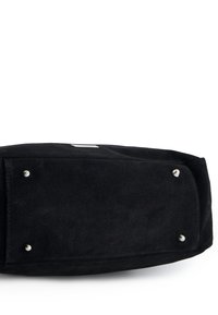 Czarna torebka z zamszu o prostokątnym kształcie, z akcentami ze srebrnej biżuterii i czterema metalowymi stopkami u dołu dla stabilności.