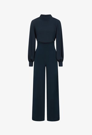 Tumedane kombekas, millel on kõrge krae, pikad puffvarrukad, sobiv vöökoht jalai pükste lõige. Sile tekstuur ja lukuga kinnitamine.