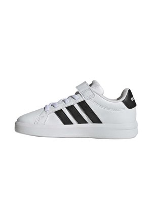 Baskets blanches Adidas avec des rayures noires, des lacets blancs et une bride Velcro, vues de la partie intérieure sur fond blanc.