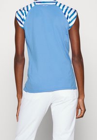 Blå sportströja med korta ärmar som har ett randigt mönster på axelpartiet. Slät textur och en kroppsnära design, lämplig för aktiv användning.