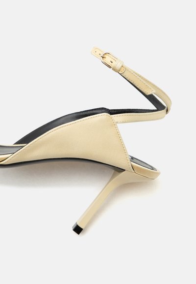 Μπεζ γυναικείο παπούτσι slingback με λεπτό τακούνι στιλέτο και ρυθμιζόμενο λουράκι με αγκράφα.