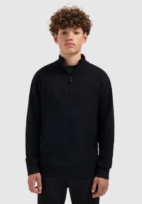 Zwarte pullover trui van textiel met een gestructureerde stof. Voorzien van een halve ritssluiting bij de kraag en lange mouwen met ribgebreide manchetten. Eenvoudig, minimalistisch design.