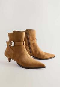 Nahka-nahkasaappaat vaaleanruskeina, joissa on terävä kärki, sivuvetoketju ja säädettävä hihna, jossa on hopeinen solki. 5 cm pystysuora korko.