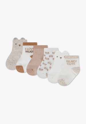 Zes paar babysokken in beige, witte en bruine tinten met berengezichten, strepen en tekst met "Ik hou van knuffels" en "Beertjes schattig."