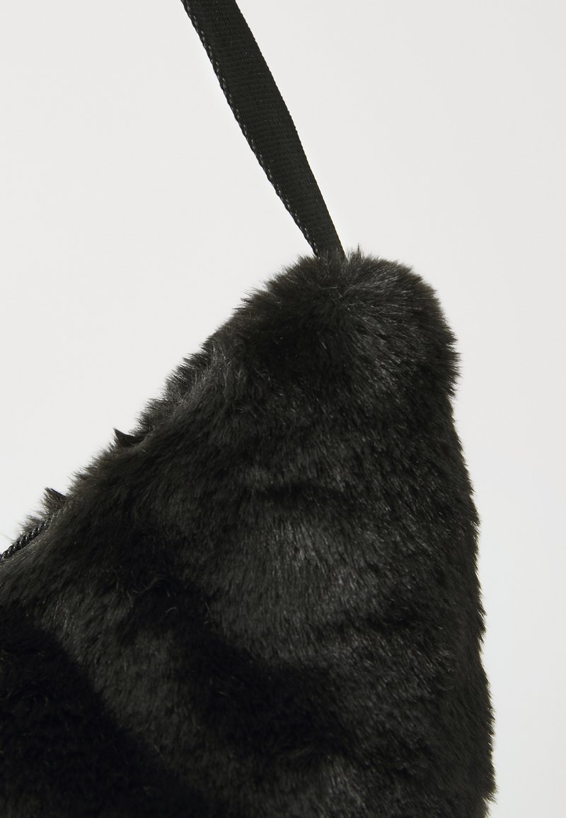 Bolso de pelo sintético negro con forma triangular, que presenta una textura suave y una correa de tela negra sujetada en la parte superior para llevar.
