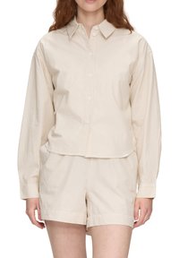 Beige gestreiftes Langarmshirt mit Knopfverschluss und Kragen. Kombiniert mit passenden Shorts, beide aus einem leichten, glatten Stoff.