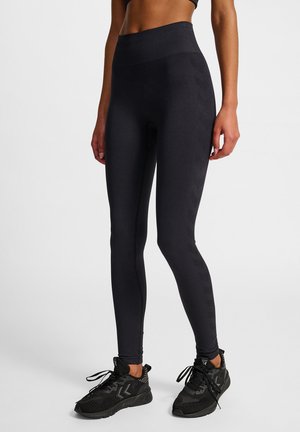 Svarta leggings med hög midja och slät textur, med ribbad midjeresår, kombinerade med svarta sportskor med ett texturerat mönster.