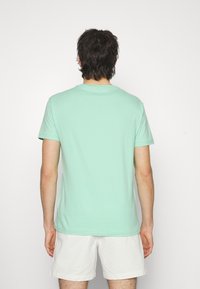 Mintgroene katoen t-shirt met korte mouwen, ronde halslijn en een gladde textuur, gezien vanuit de achterkant.