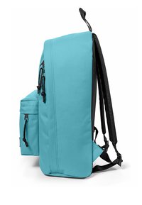 Mochila turquesa de forma rectangular, con detalles en negro, bolsillos con cremallera, material texturizado y correas de hombro ajustables.