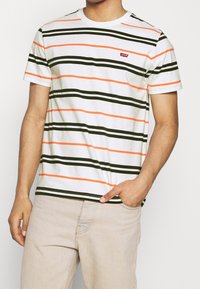 Gestreepte T-shirt met korte mouwen in het wit, met donker groene, oranje en lichtoranje horizontale strepen, voorzien van een klein rood Levi's logo.
