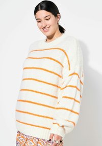 Übergroßer weißer Pullover mit orangenen Streifen, strukturierter Strick, gerippte Bündchen, runder Ausschnitt und leicht überschnittene Schultern.