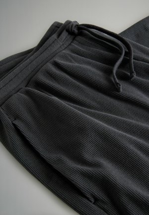 Dark gray ribbed fabric sweatpants with an elastic waistband and drawstring, folded on a flat surface.