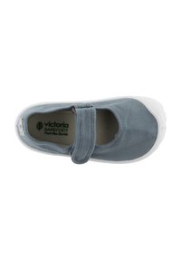 Zapatos Mary Jane de lona gris con una correa de Velcro, punta redonda y suela de goma blanca. El interior presenta un branding verde y un forro texturizado.