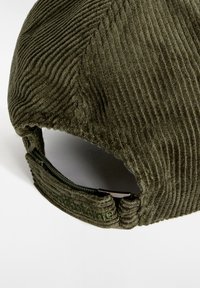 Cappello in corduroy verde oliva con texture rigata, cinturino posteriore regolabile e hardware metallico. Design semplice e strutturato con dettagli cuciti.