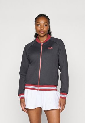 Donkergrijze zip-up jack met raglanmouwen, rode accenten en gestreepte zoom. Voorzien van een geborduurd logo op de linkerborst. Sterke structuur.