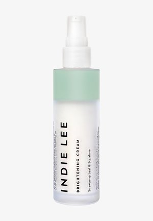 Clear glass bottle with a mint green cap. Features bold black text labeling "INDIE LEE BRIGHTENING CREAM," containing strawberry leaf and squalane.