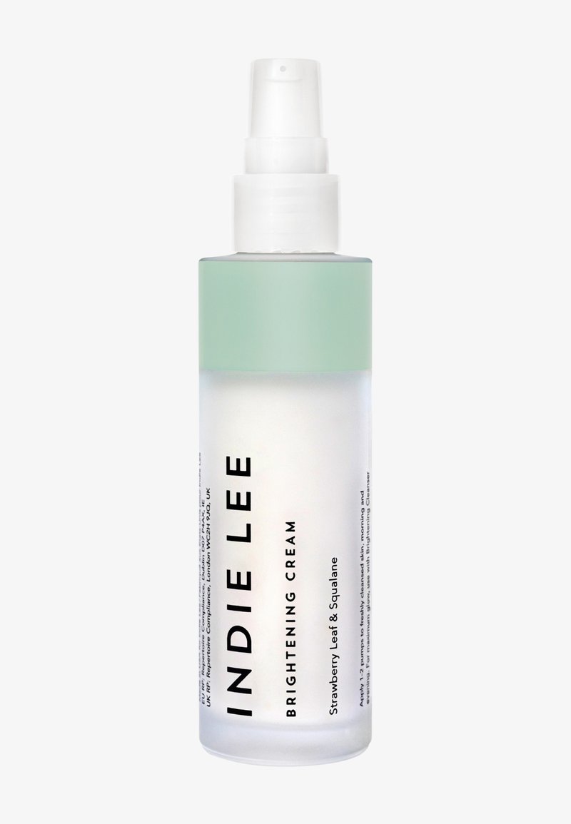 Bouteille en verre clair avec un capuchon vert menthe. Présente un texte noir en gras indiquant "CREME ÉCLAIRCISSANTE INDIE LEE", contenant des feuilles de fraise et du squalane.