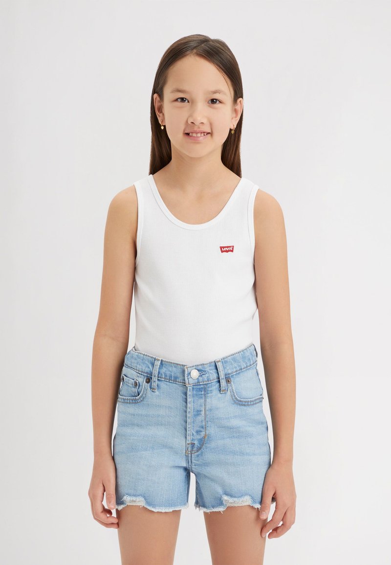 Top in cotone bianco a coste con un piccolo logo rosso di Levi's, abbinato a pantaloni corti di jeans blu chiaro con orli sfrangiati e bottoni.