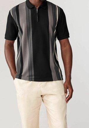 Black polo shirt featuring vertical stripes in gray and cream, with a zippered collar. Made of ribbed texture fabric.