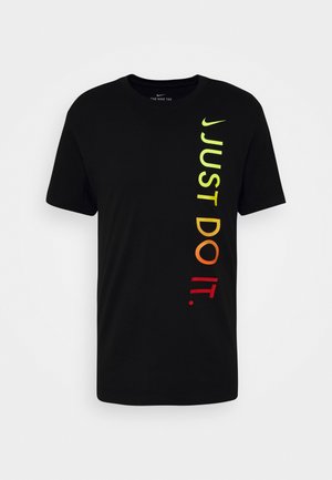 T-shirt Nike noir à manches courtes avec le texte vertical "JUST DO IT." en dégradé du jaune au rouge sur le côté droit et un petit logo Nike en forme de virgule jaune au-dessus.