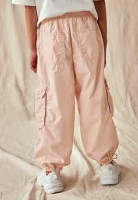 Lichtroze cargobroek met elastische enkels, achterzakken en zijzakken. Gemaakt van een lichte stof, heeft een relaxed fit.