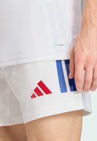 Witte atletische shorts met rode en blauwe Adidas-logo details. Voorzien van ademende Climacool-stof met een gladde, gestructureerde afwerking.