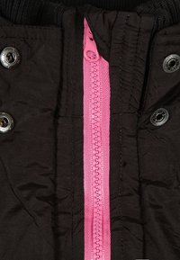 Czarna kurtka z wyrazistym różowym zamkiem na środku, wyposażona w srebrne zatrzaski i żebrowany materiał przy kołnierzu.