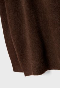 Tessuto in maglia marrone con una superficie morbida e testurizzata, caratterizzato da un drappeggio morbido e un orlo arrotondato sul fondo.