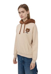 Felpa beige con cappuccio in pelliccia sintetica marrone, con grafica di un orso e la scritta "RELAX". Tasca a marsupio sul fronte, polsini a costine e vestibilità comoda.
