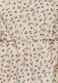 Tessuto con motivo floreale su uno sfondo crema, decorato con piccoli fiori rosa e bordeaux e steli verdi; dettaglio arricciato in vita.
